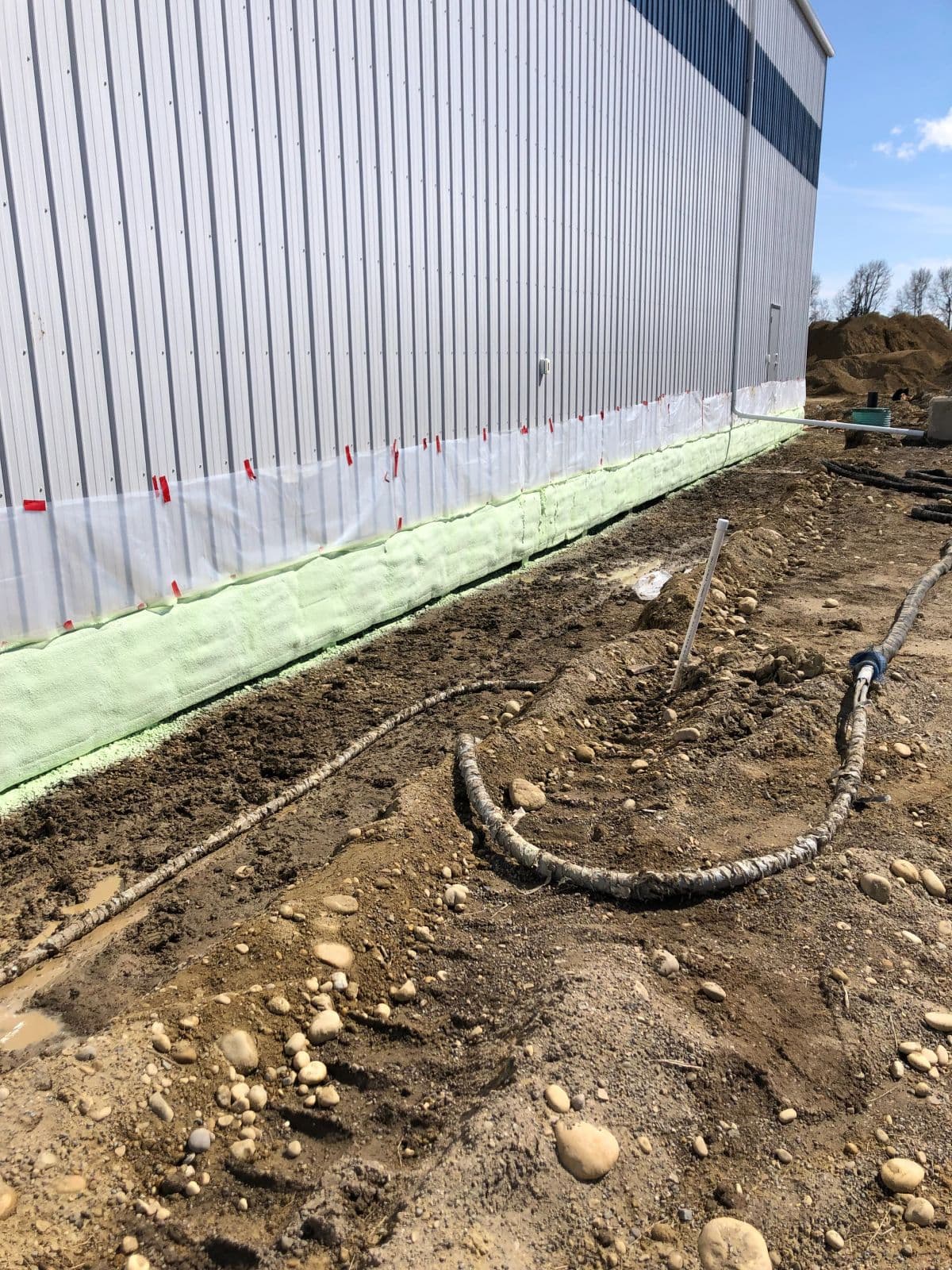 Commercial foundation spray foam application Commercial building foundation coated in Genyk Boreal Nature Elite 2 lb closed-cell spray foam with a coiled spray hose